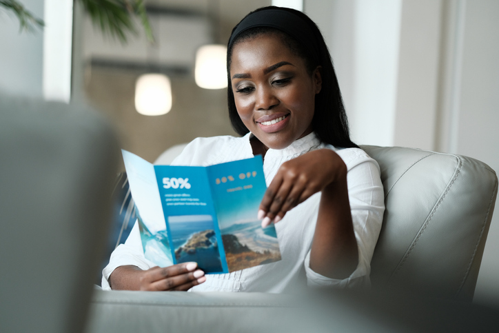 African American Woman Sitting On Sofa, Reading A Travel Flyer Advertising Promotional Discounts For Vacations. (African American Woman Sitting On Sofa, Reading A Travel Flyer Advertising Promotional Discounts For Vacations., ASCII, 112 components, 11